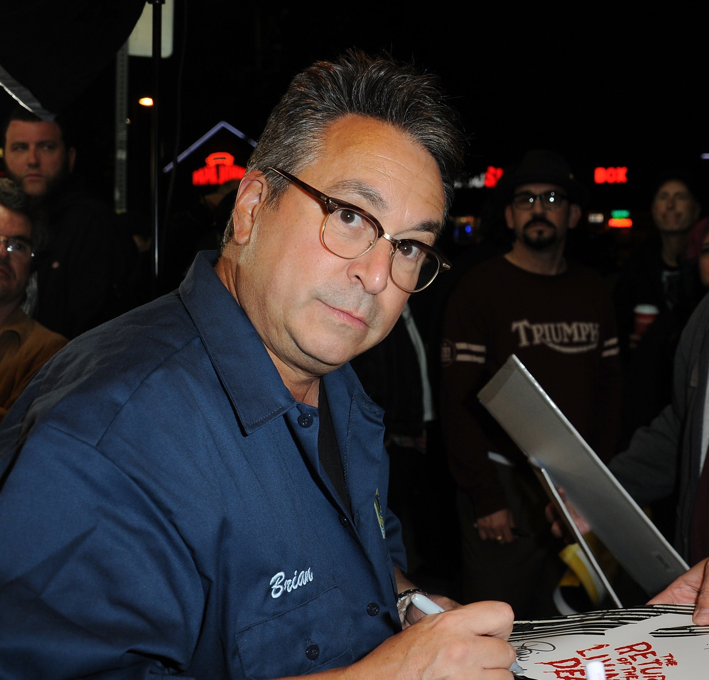 Brian Peck in glasses and blue shirt signing autographs for fans