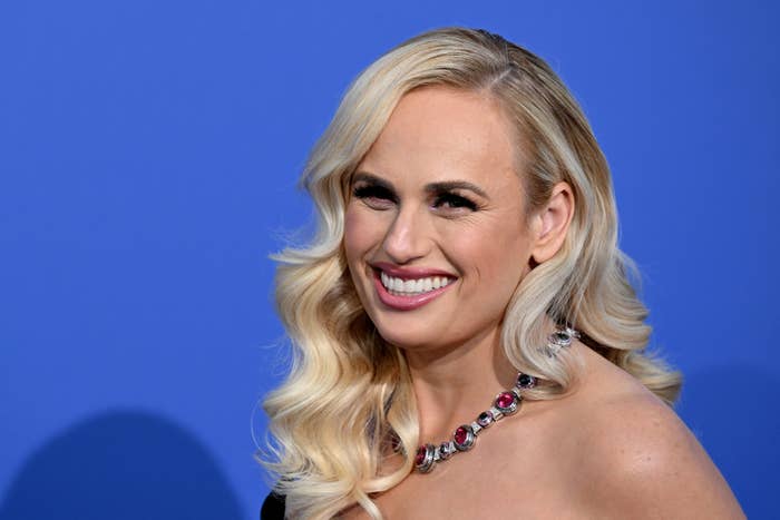 Rebel smiling, wearing a gemstone necklace, at a media event