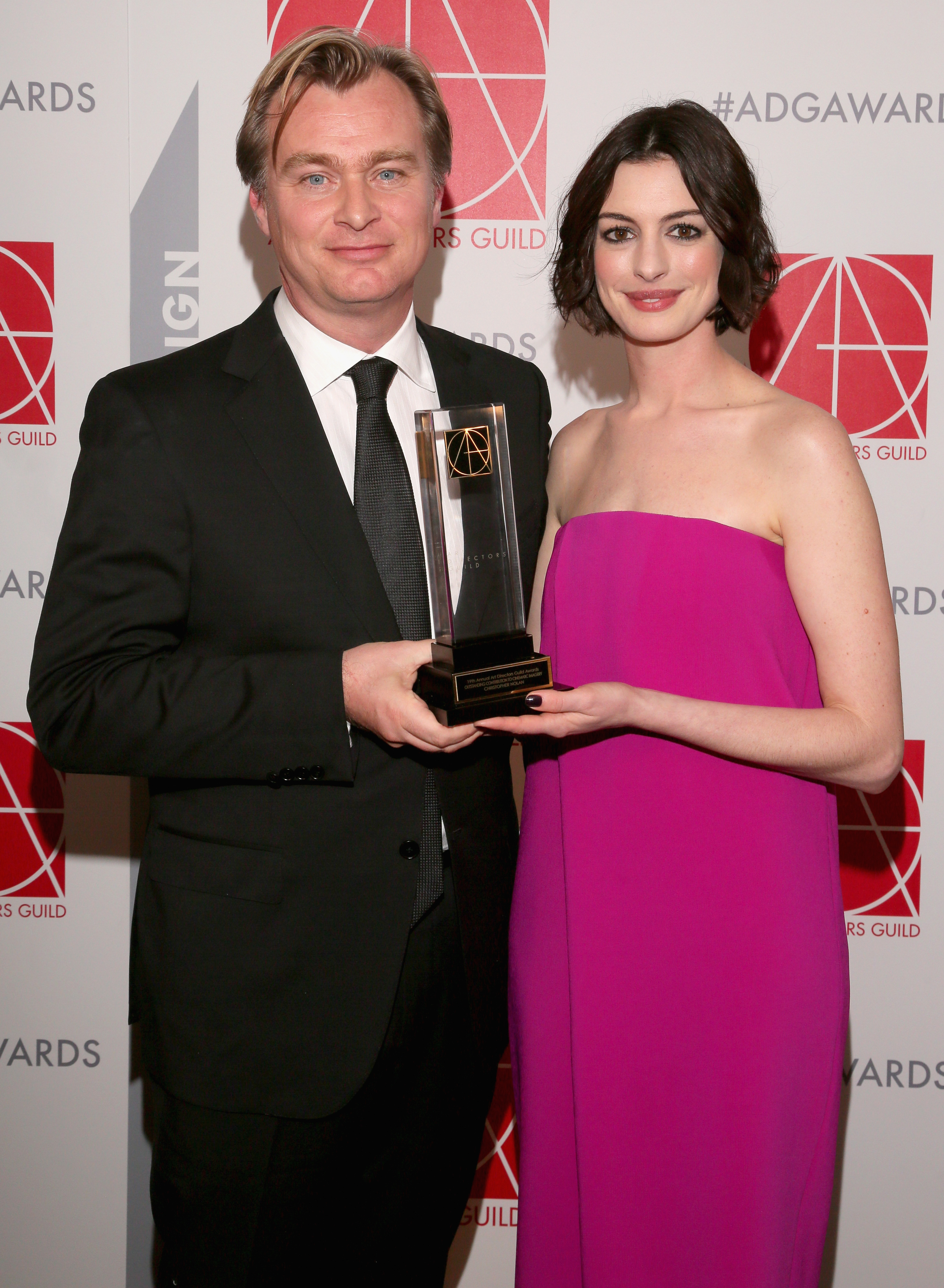 Christopher Nolan and Anne Hathaway together at an event and holding an award