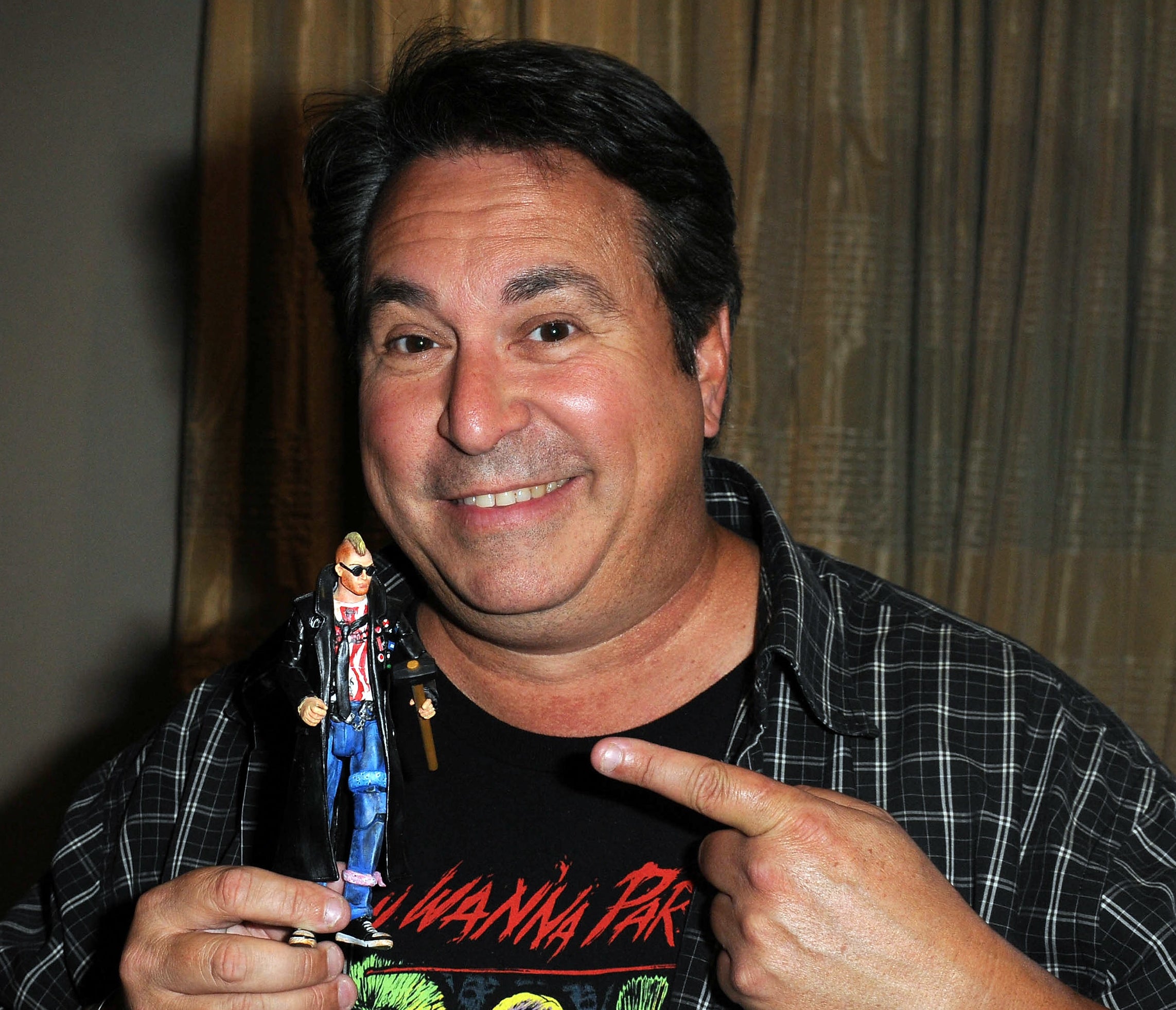 Brian Peck smiling and holding and pointing to a figurine