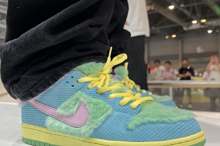 Close-up of a sneaker with furry blue texture, yellow laces, and a pink swoosh, at a sneaker event
