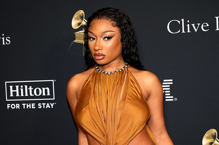 Megan Thee Stallion posing in a stylish draped dress at a Clive Davis event