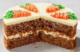 Carrot cake with cream cheese frosting and carrot decorations on top, cut into to show layers