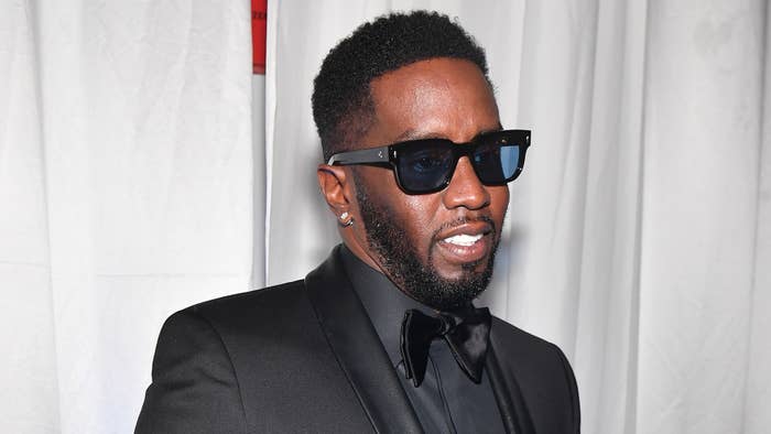 Music artist in a black tuxedo and sunglasses poses for a photo