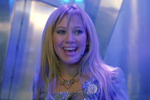 Hilary Duff as Lizzie McGuire smiles wearing a headset and a decorative top with a corsage in The Lizzie McGuire Movie