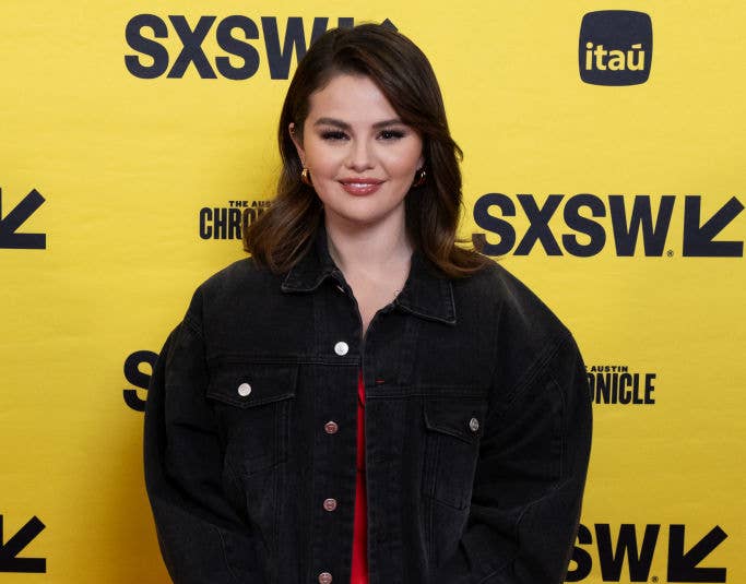Selena Gomez in a black denim jacket over a red dress posing at SXSW event