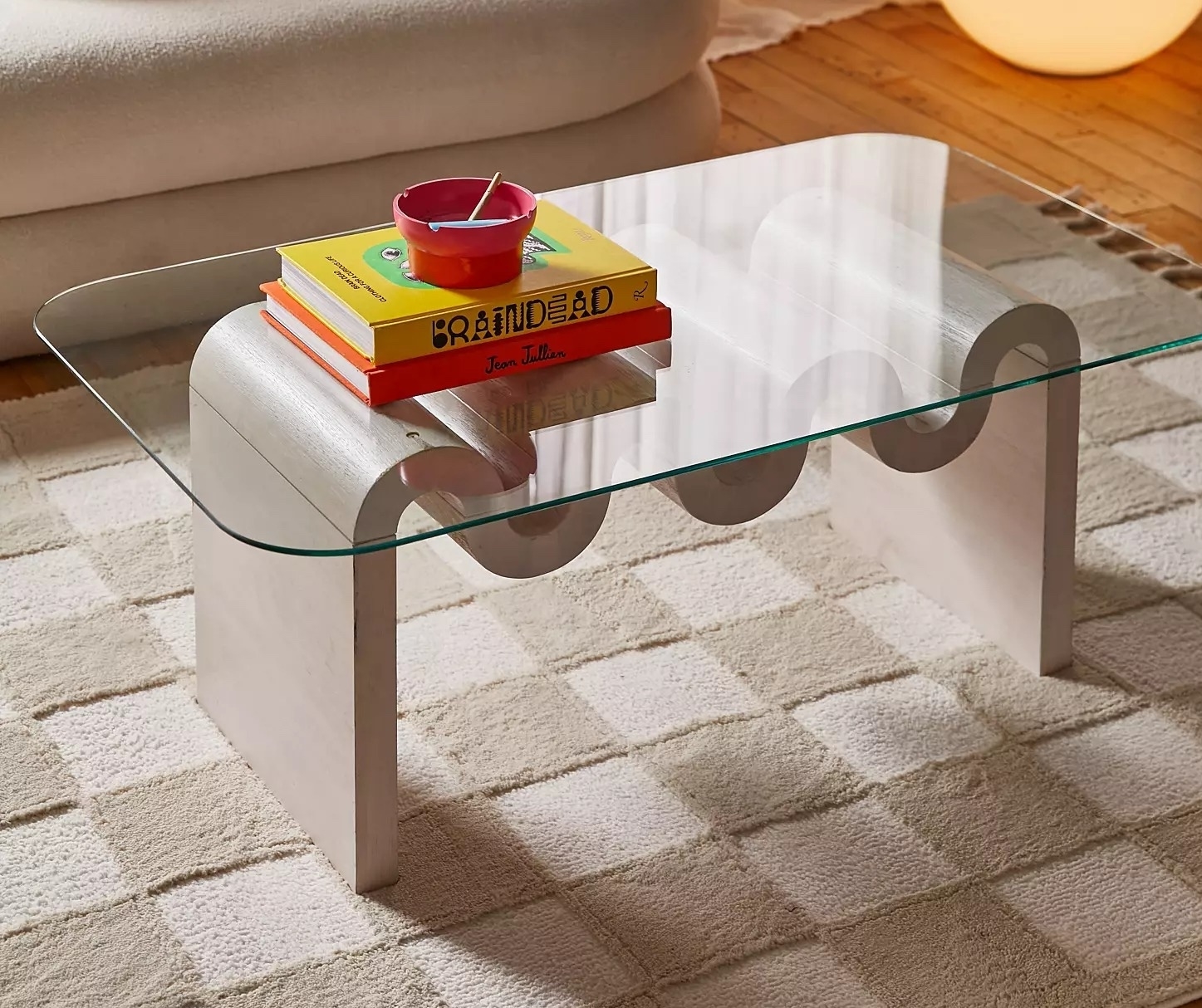 Modern glass coffee table with curved edges and books on top