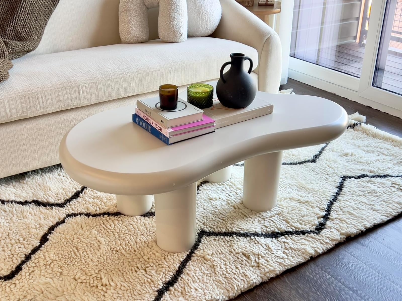Modern living room with a stylish curved coffee table adorned with books and decorative items
