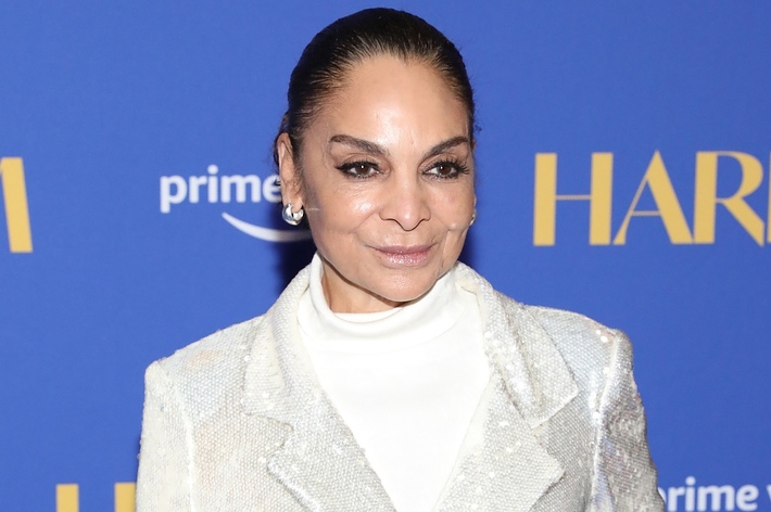 Jasmine Guy posing, wearing a white turtleneck and a textured jacket, at the "Harlem" event