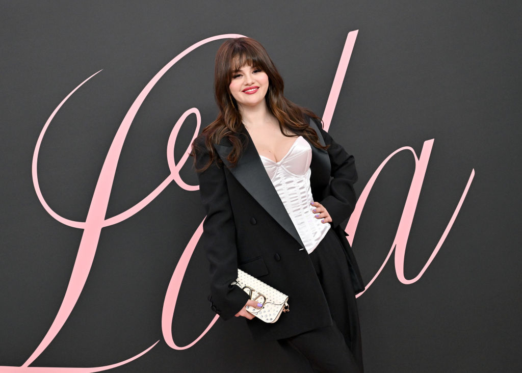 Selena in an oversize blazer and corset-style top posing at a media event