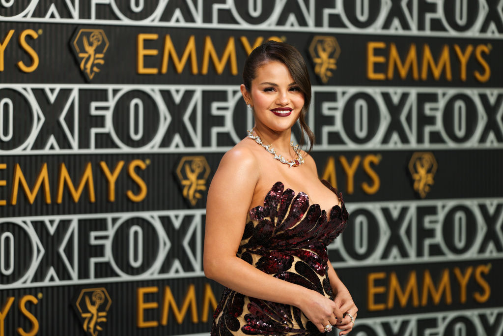 Selena Gomez in a strapless dark gown with a metallic design, smiling at the Emmys