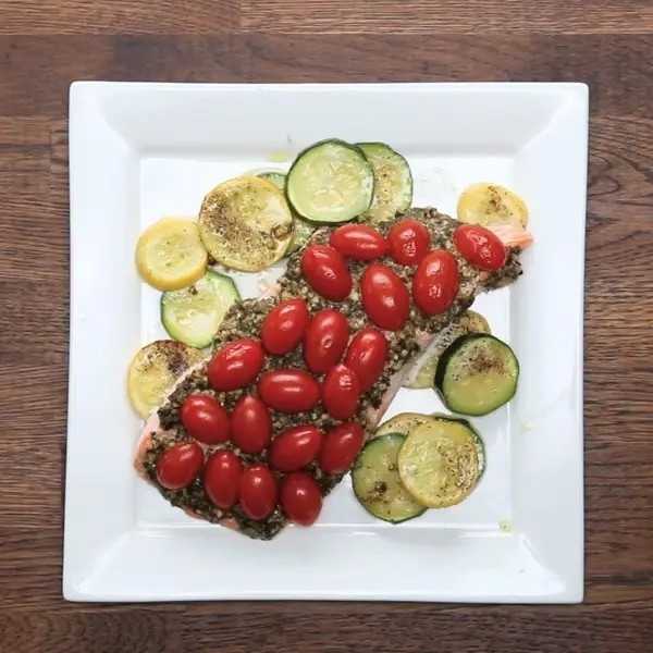 Open-faced sandwich with tomatoes, avocado, and cucumbers on a square plate