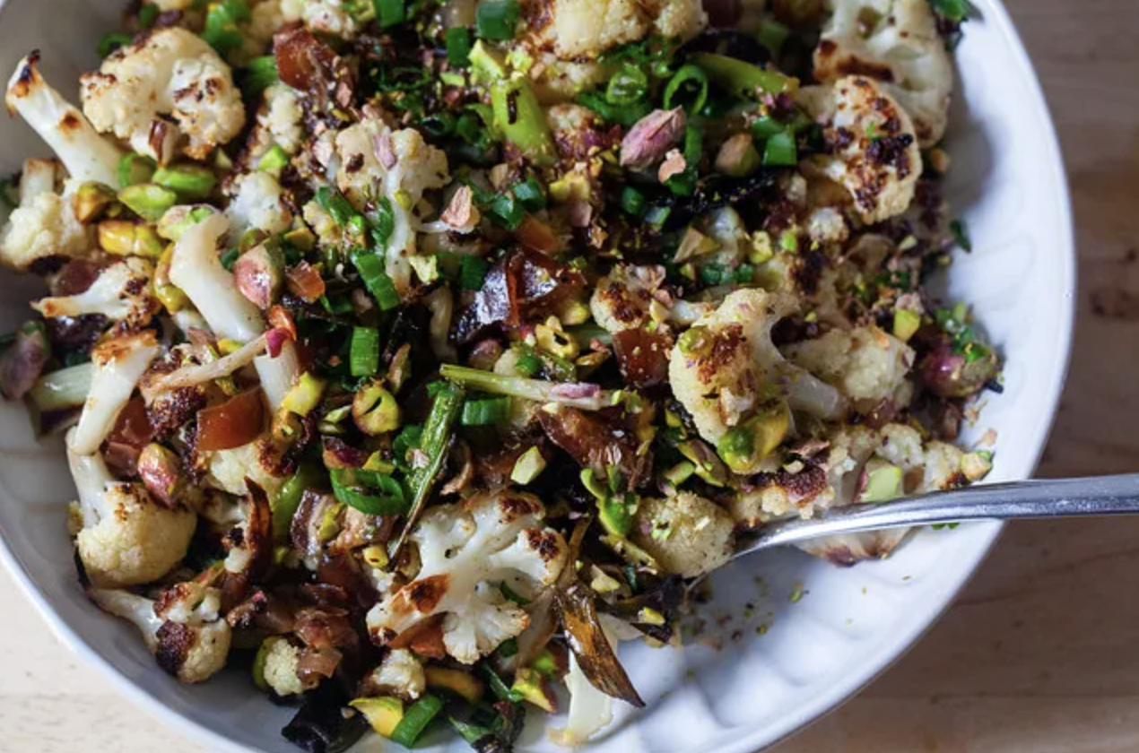 Roasted cauliflower salad with mixed nuts and herbs in a bowl with a serving spoon