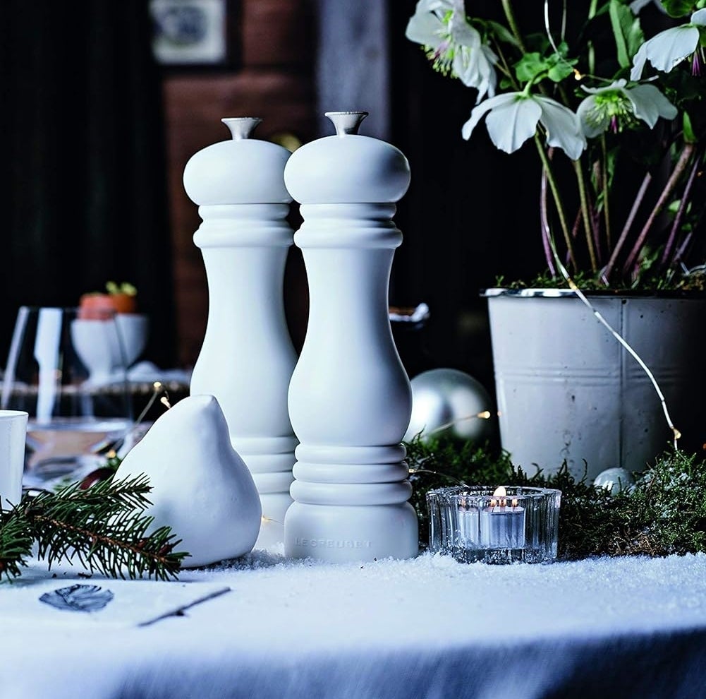 Elegant salt and pepper shakers on a festive dining table setting with plants and candle
