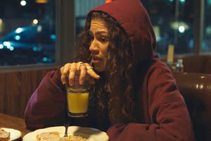 Rue from Euphoria sipping orange juice at a diner table