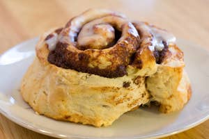 A freshly baked cinnamon roll with icing on a plate