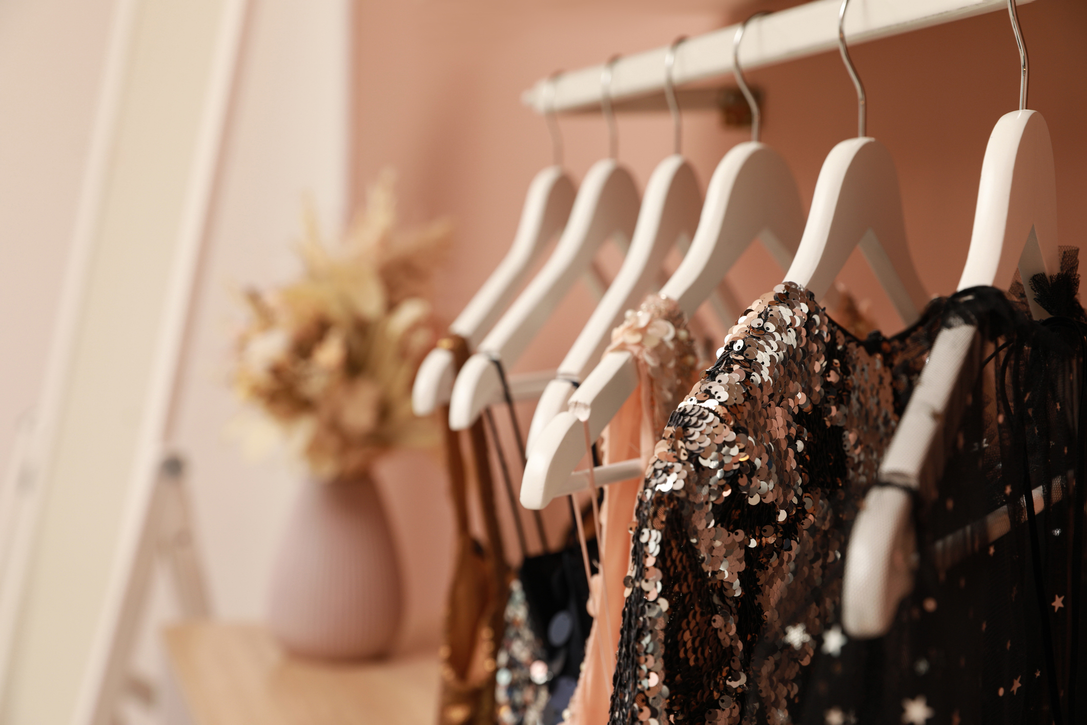 Assorted elegant garments on hangers, featuring sequined designs, likely for a professional or upscale setting