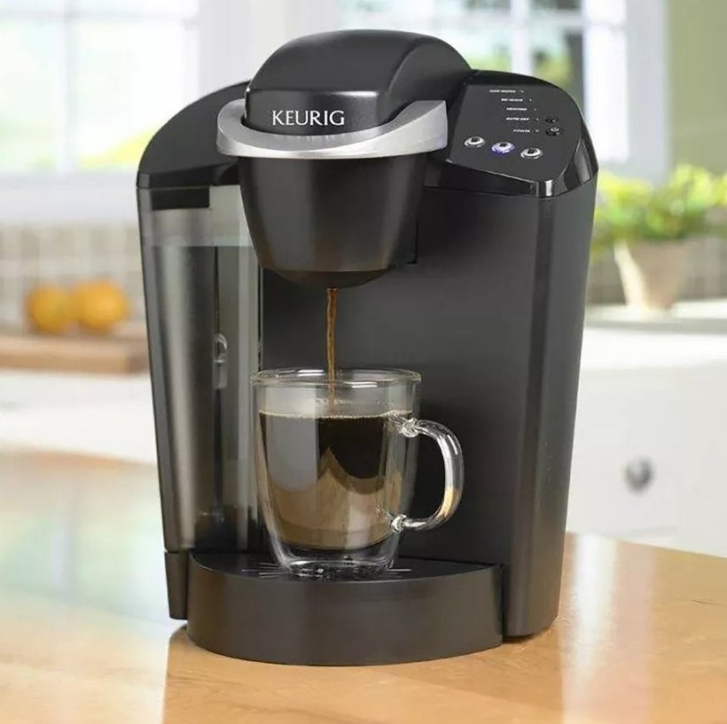 Keurig coffee maker brewing into a clear mug on a kitchen counter