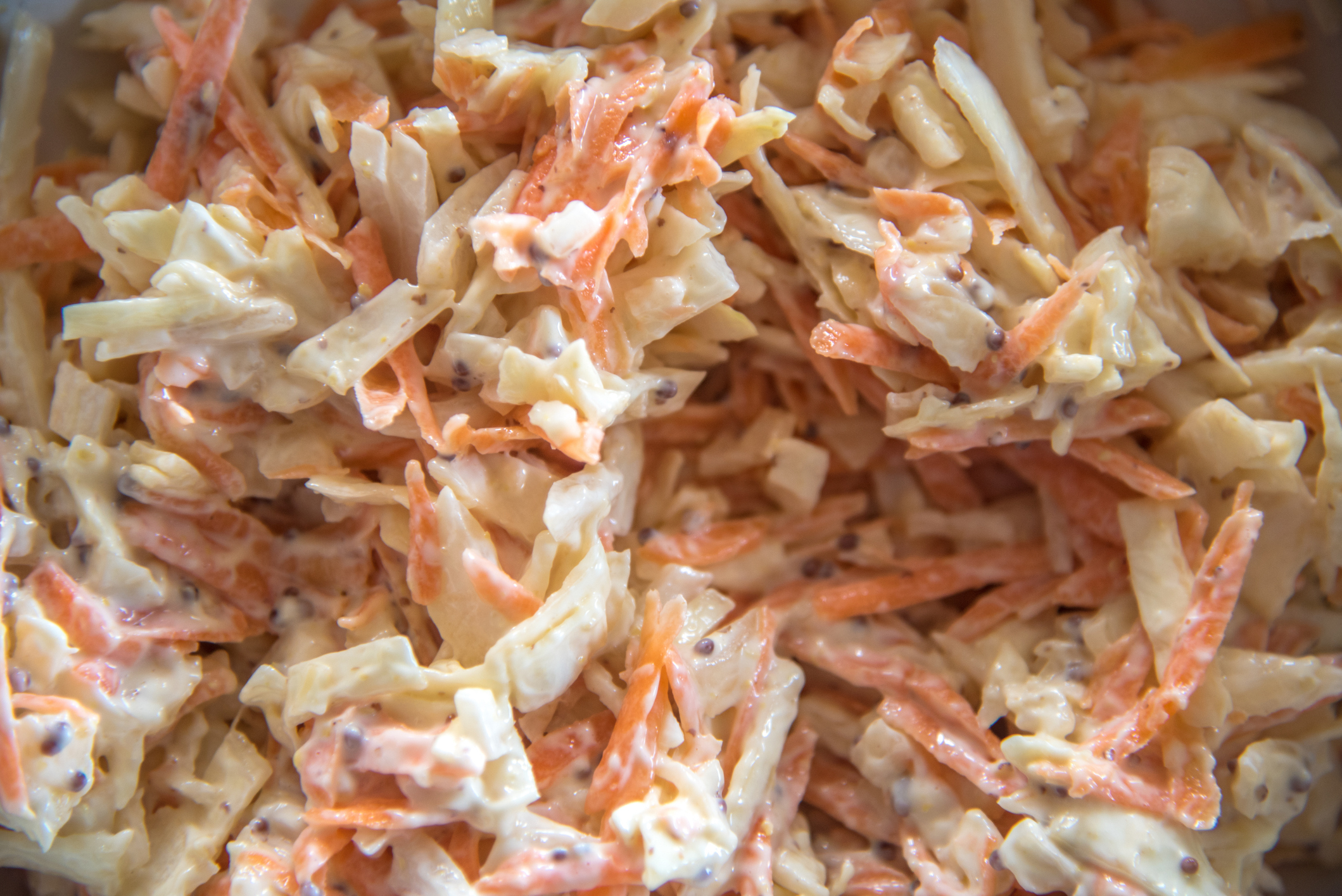 Close-up of coleslaw with shredded carrots and cabbage dressed in mayonnaise