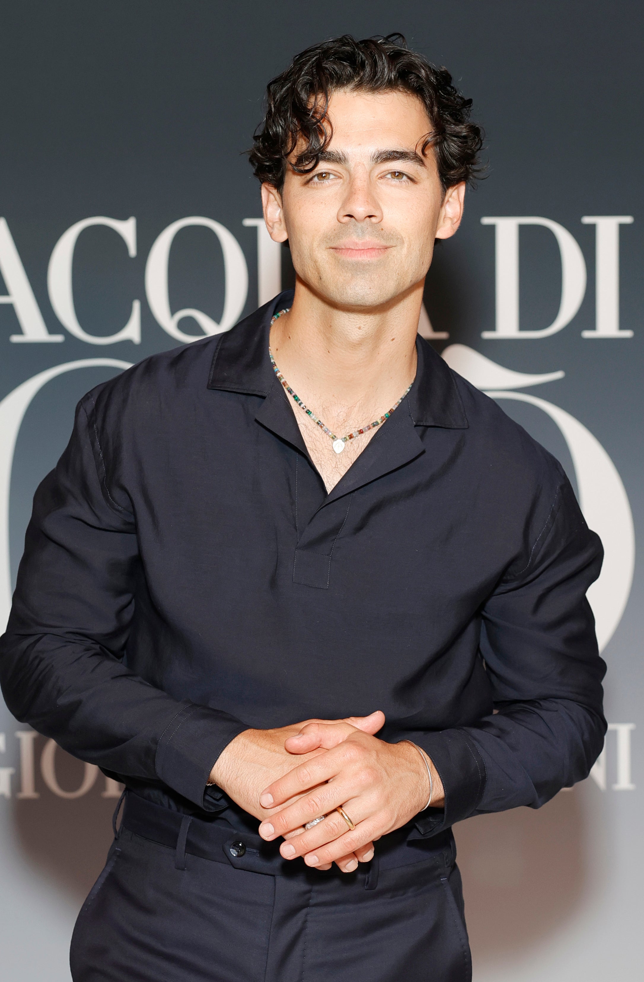 Joe Jonas in a silk button-up shirt and trousers at an Acqua Di Gio event