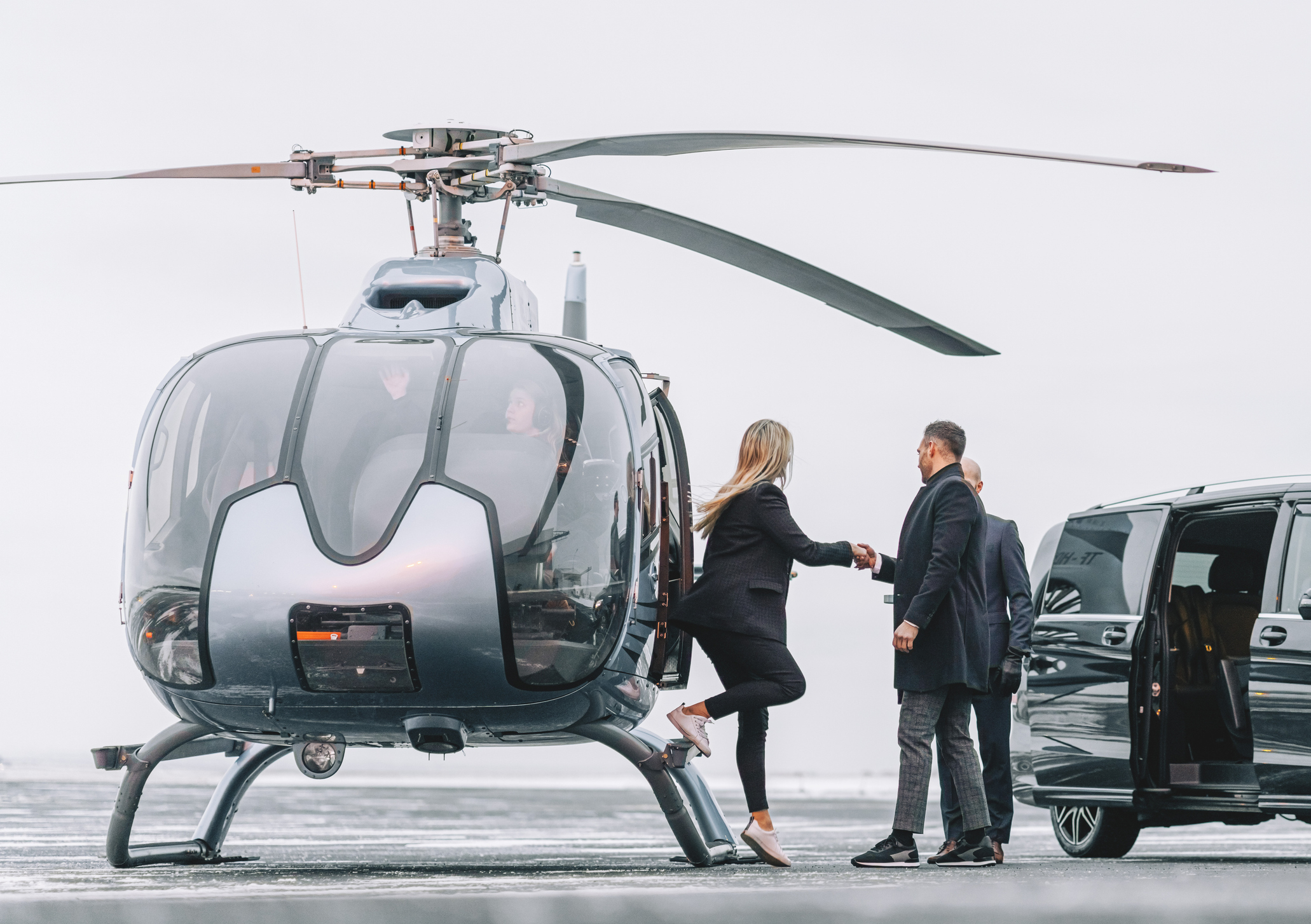 Business professionals boarding a helicopter next to a car