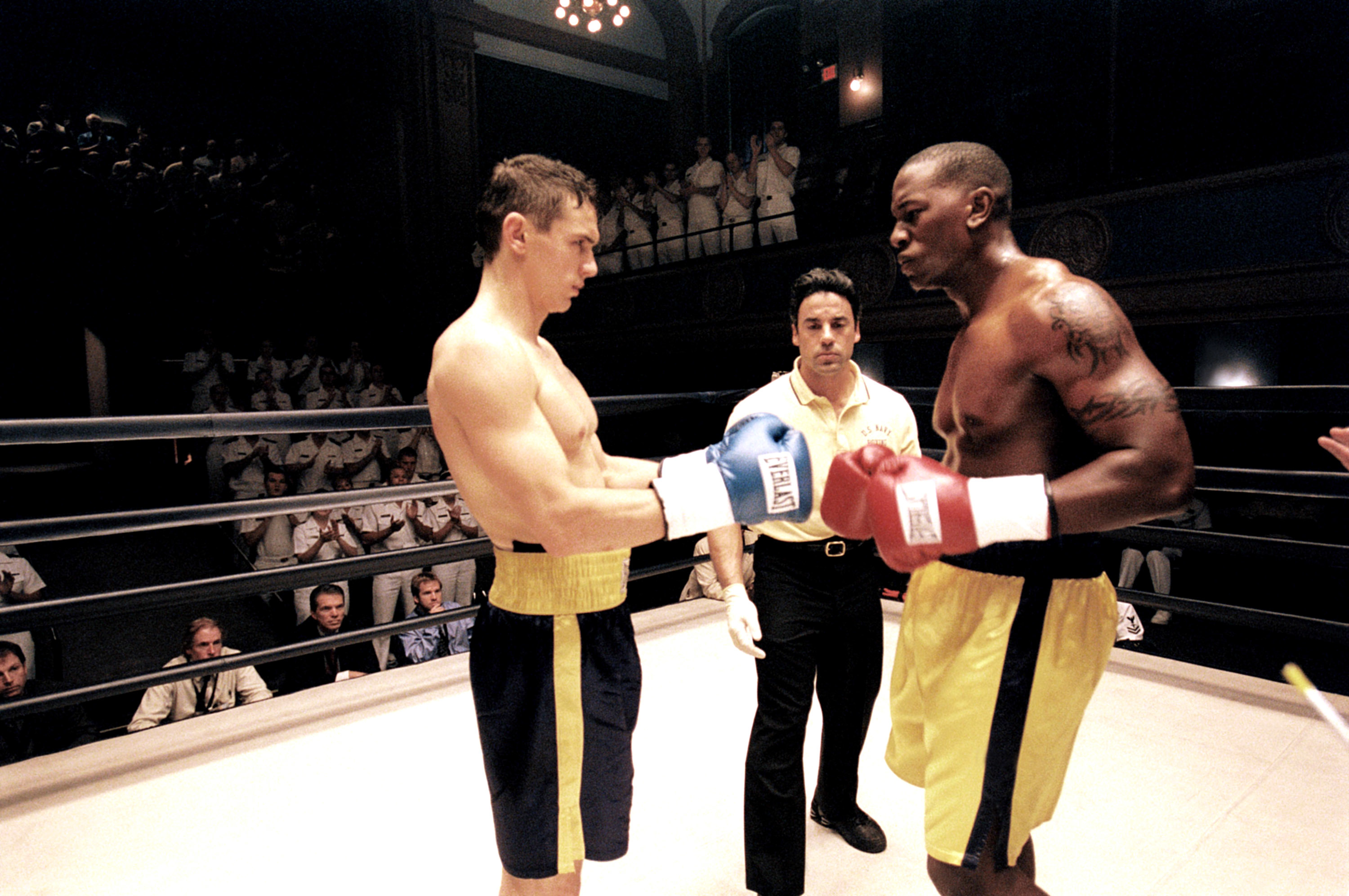 James and Tyrese in character as boxers face off in a ring with a referee between them, audience in the background