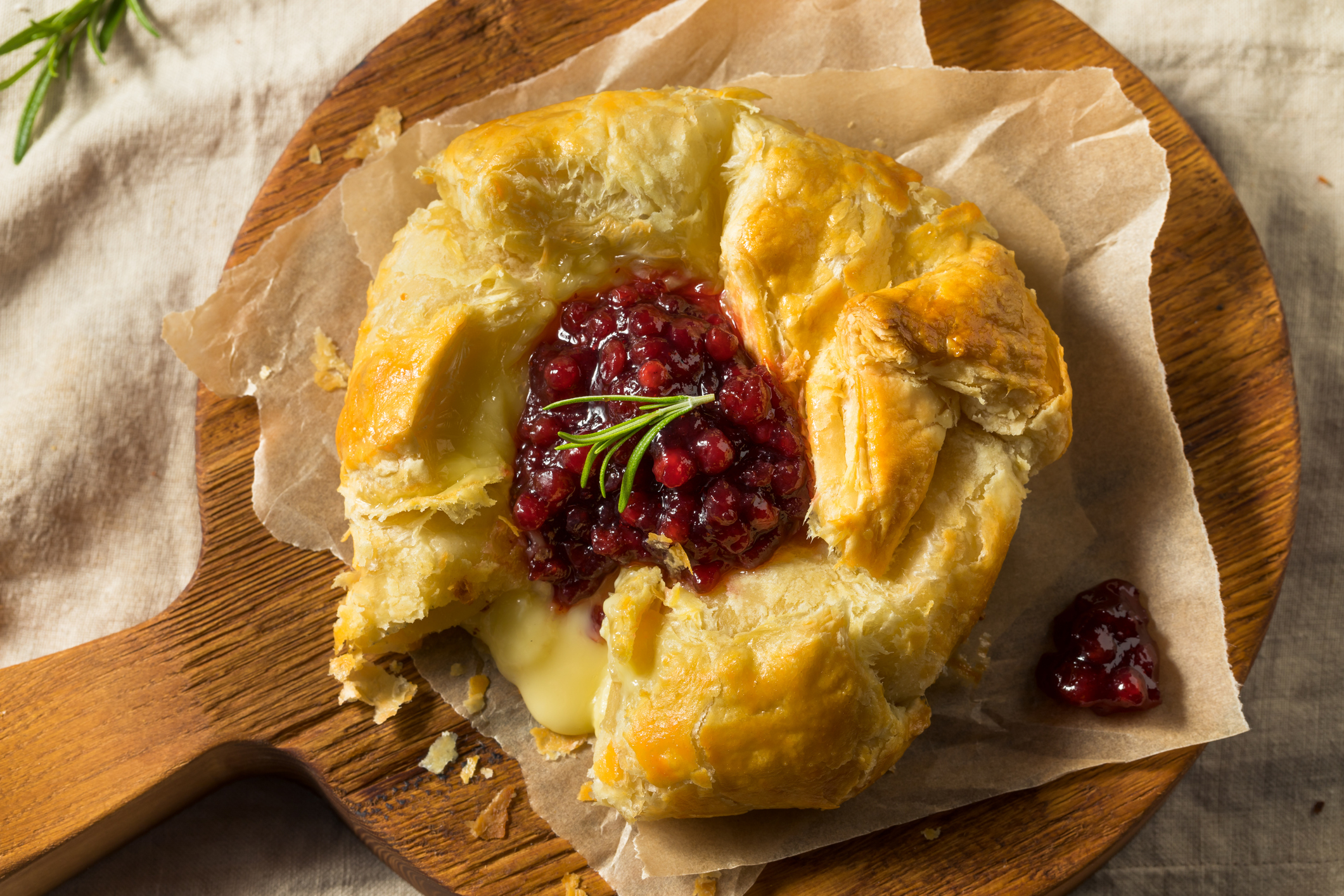 Homemade baked brie with raspberry jam on a wooden serving board