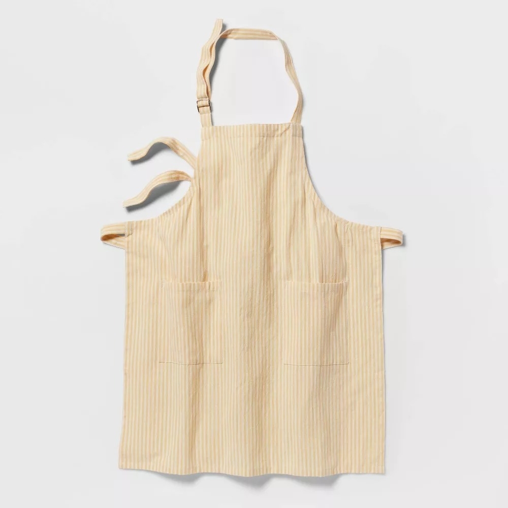 yellow and white striped apron with neck strap and two front pockets against a white background