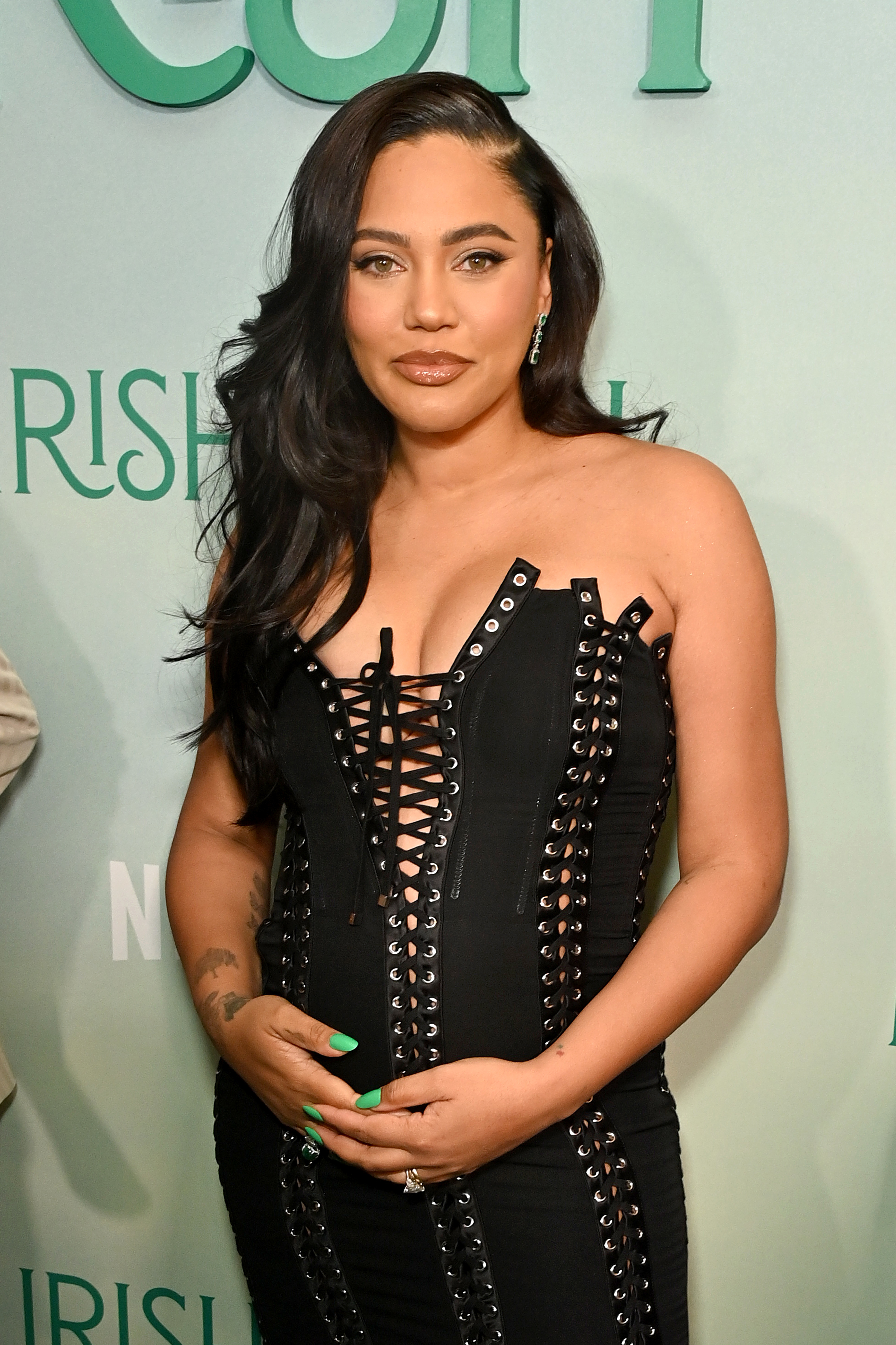 Ayesha in a black studded corset dress posing with hand on hip