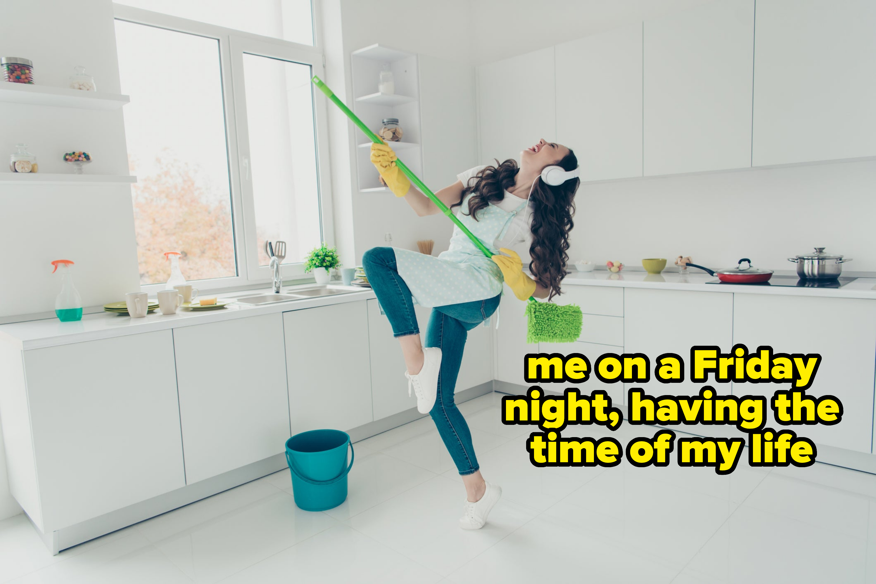 Woman pretending to play guitar with a mop while cleaning the kitchen