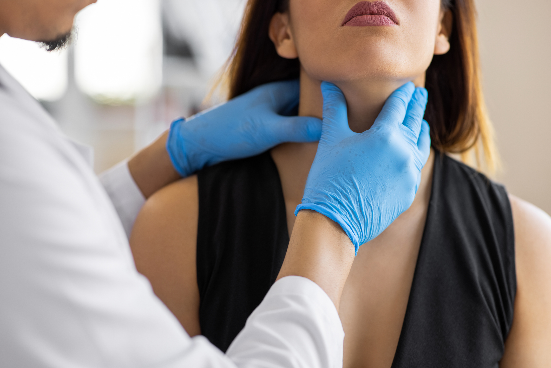 Doctor palpating a patient&#x27;s neck for a medical examination