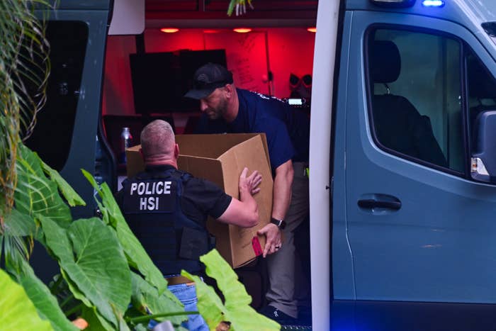 Law enforcement officials remove a box from a vehicle amidst an investigation