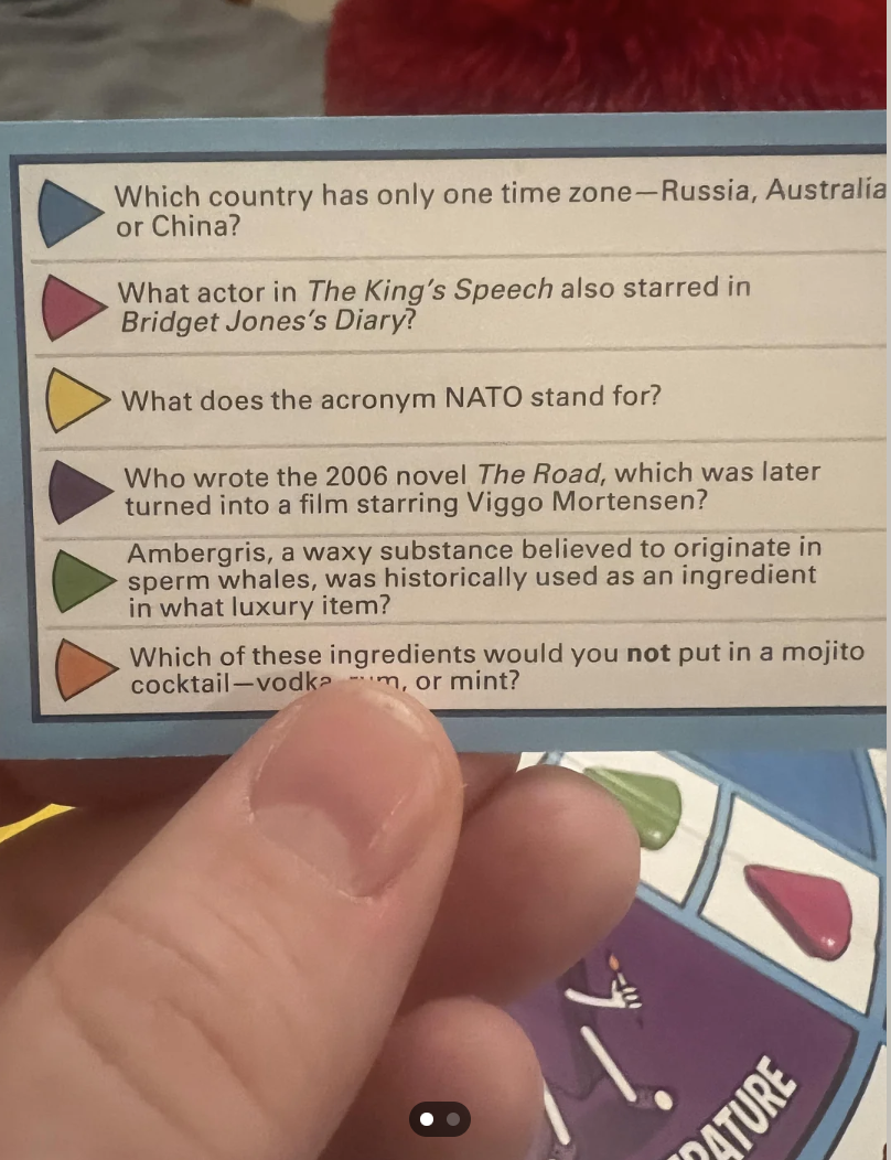 A hand holding a trivia card