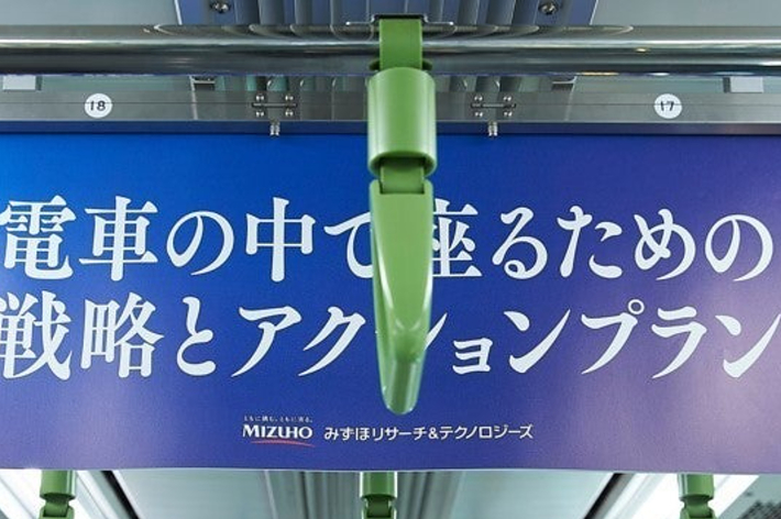 電車内の吊り広告で「青春の中で起こるあの　躍動とアグレッシブ」の文字が書かれています。