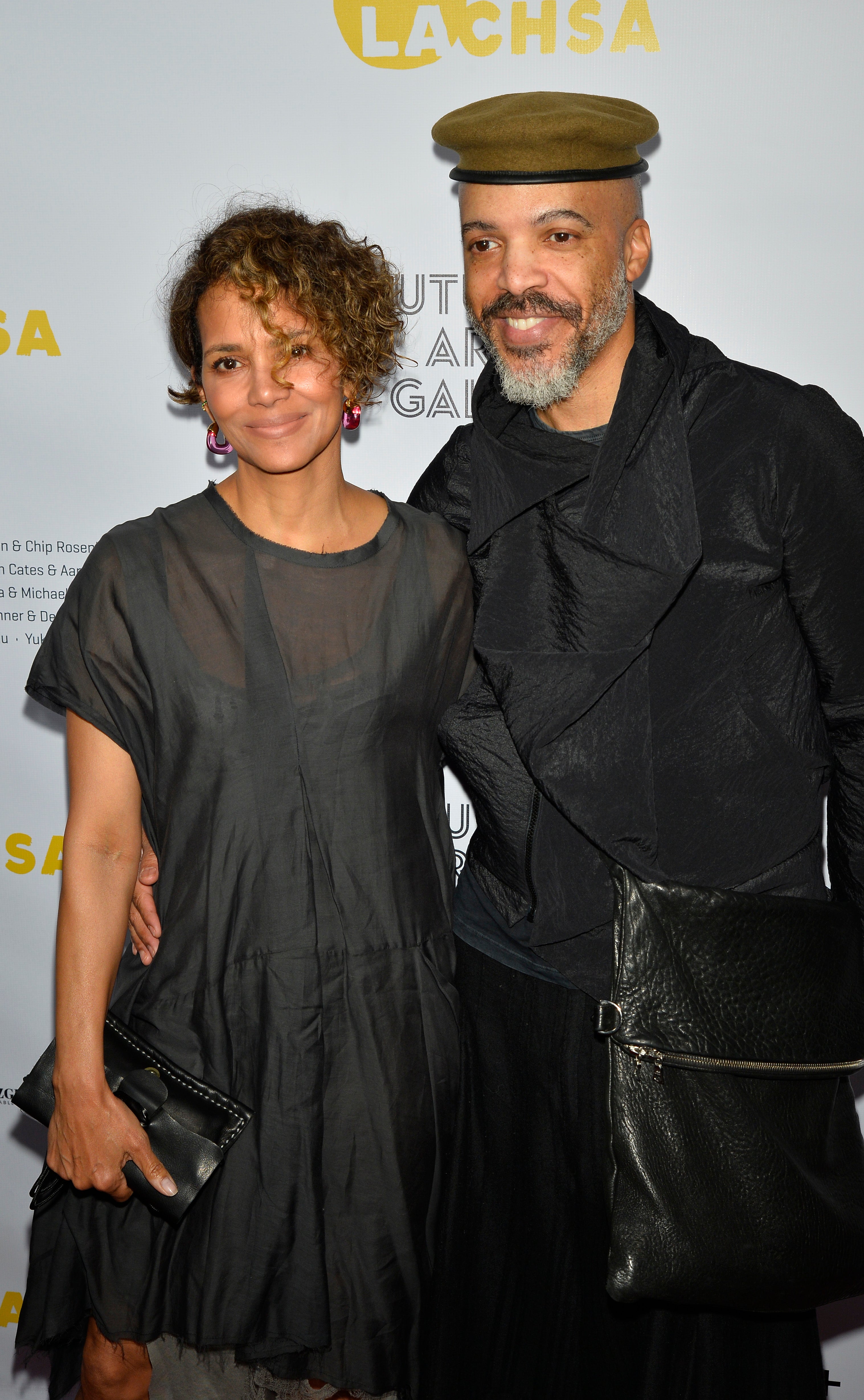 his arm around halle as they pose at an event
