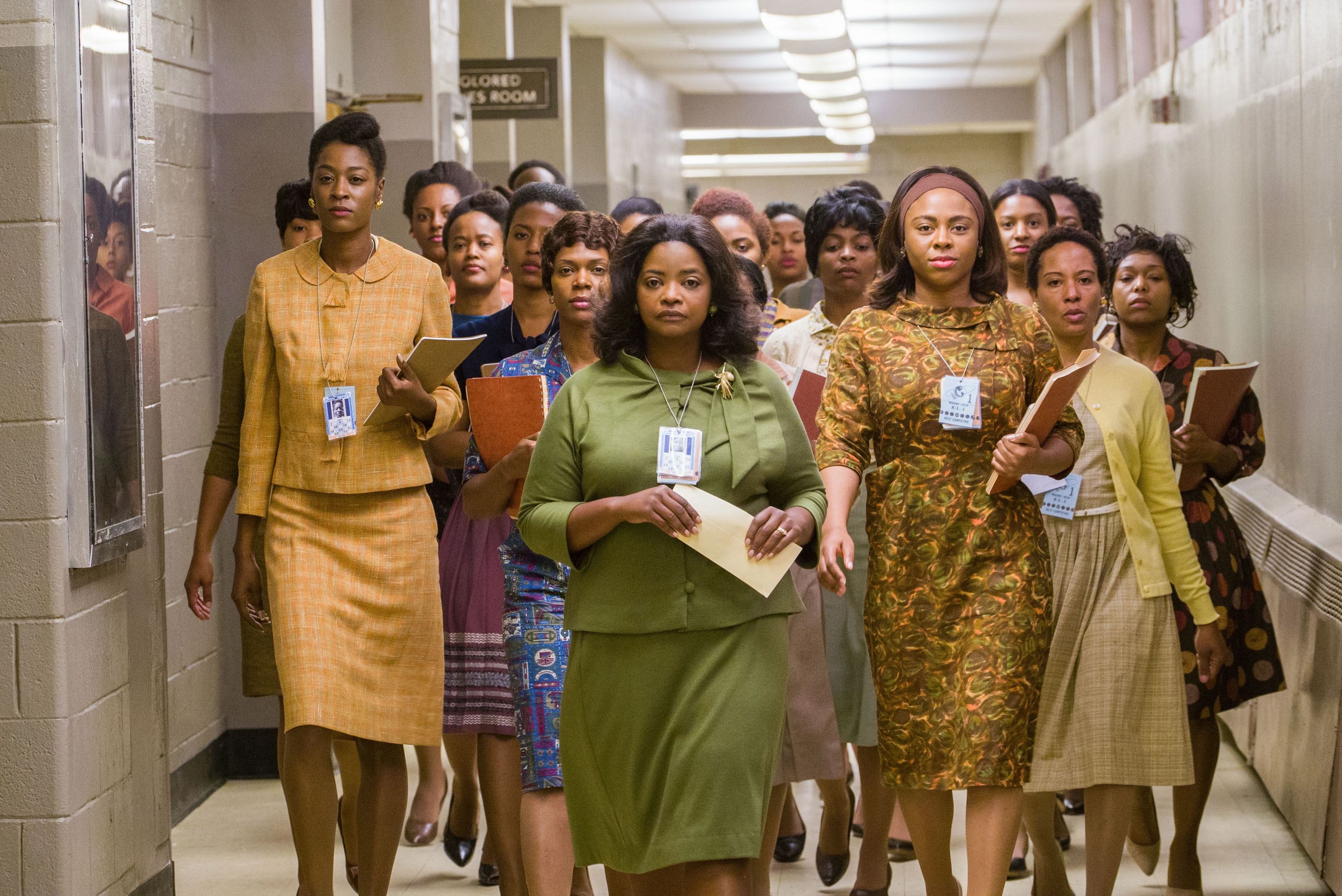 A group of women, including Octavia Spencer, in work attire walking purposefully through a corridor in a scene from Hidden Figures