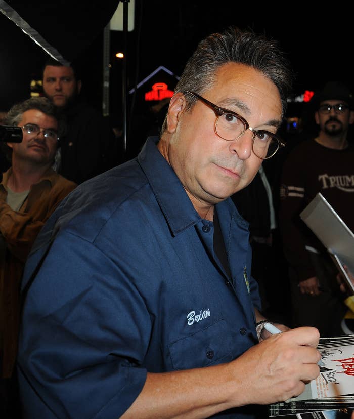 Andy Garcia signing autographs at an event, wearing a casual shirt with onlookers in the background