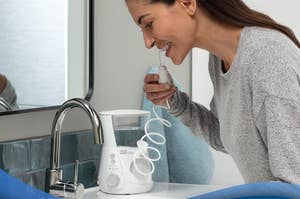 Person using a water flosser near a sink
