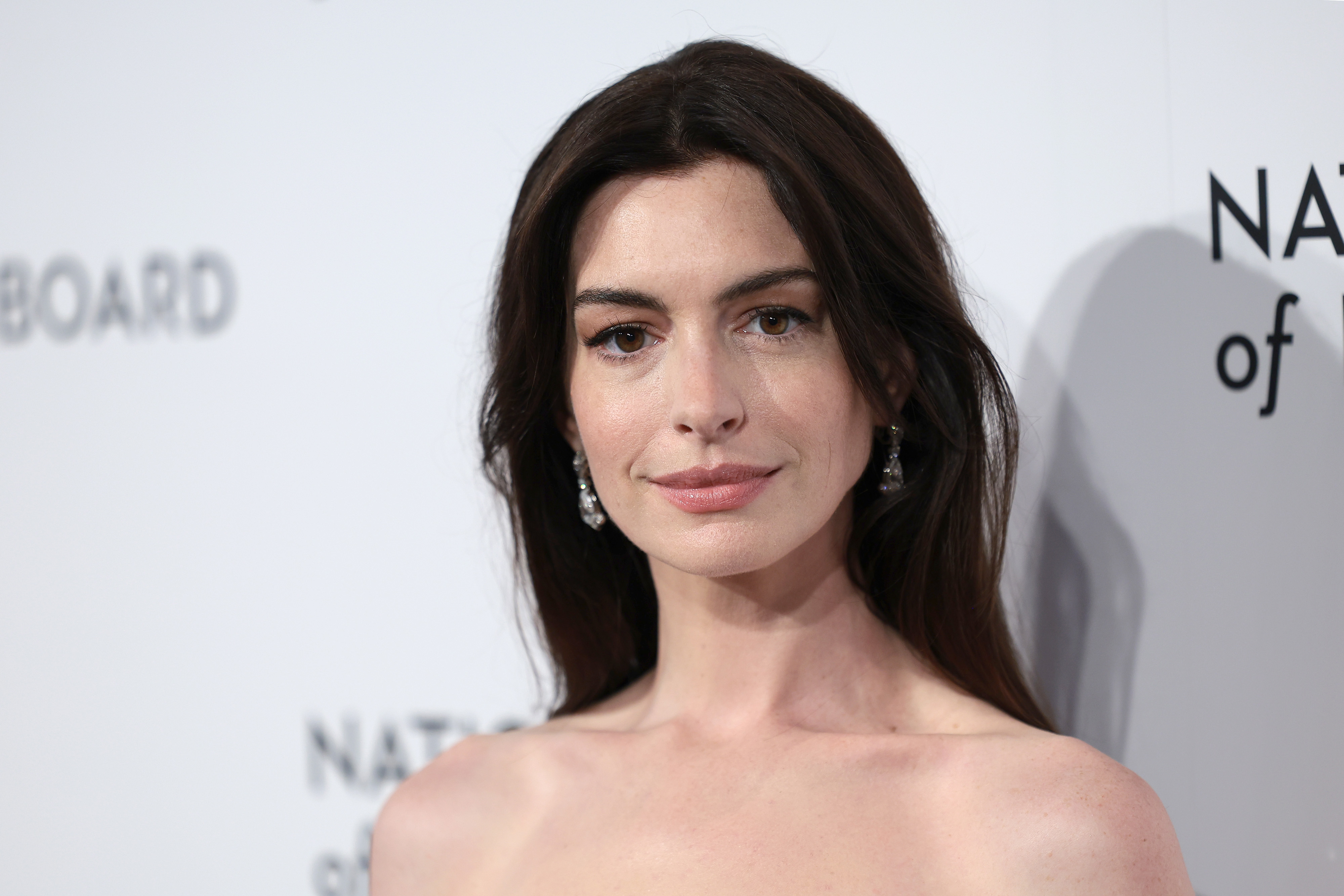 Anne Hathaway wearing a strapless gown and drop earrings at a formal event
