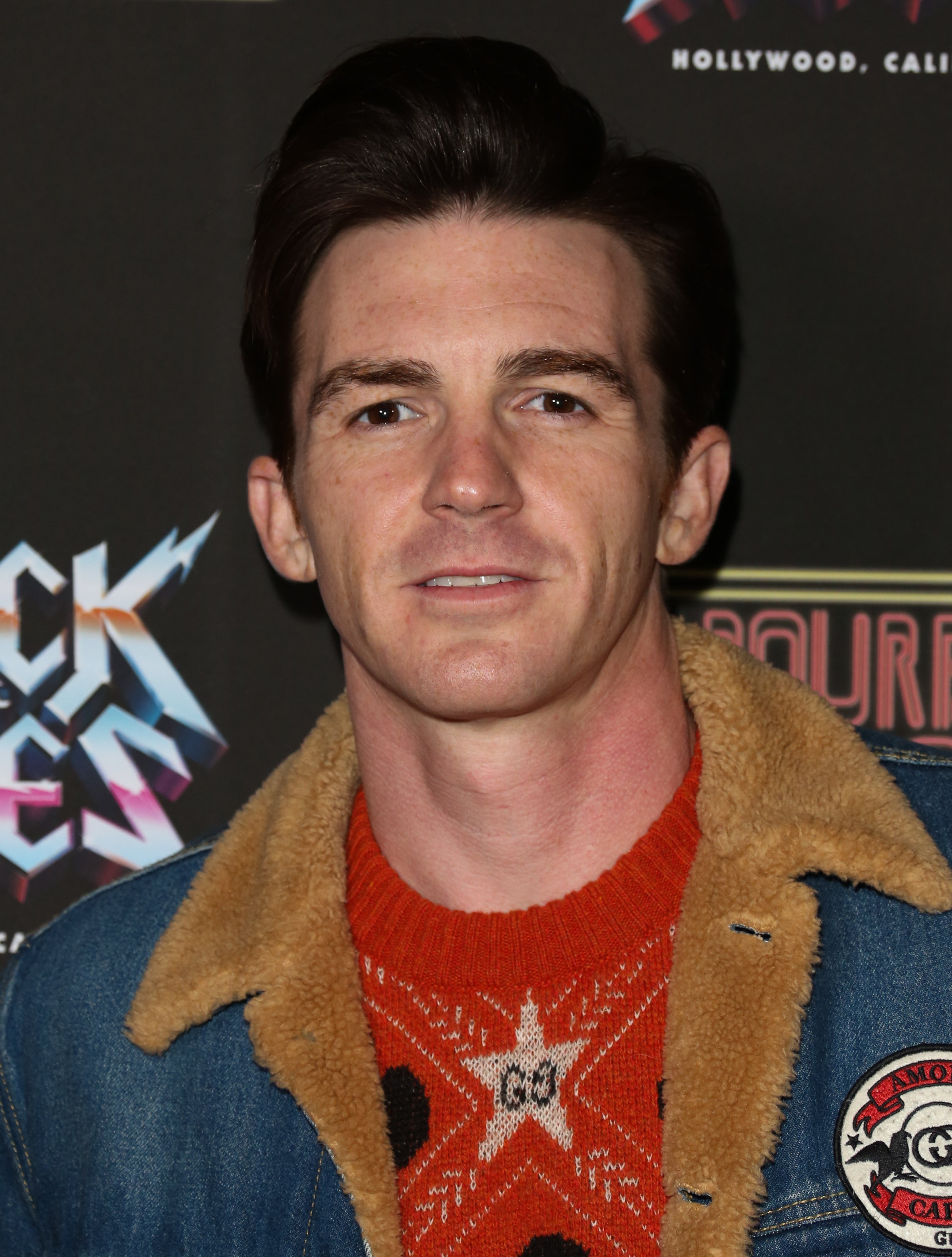 Drake Bell in a denim jacket over a star-patterned shirt, smiling at a &quot;Rock the Vote&quot; event