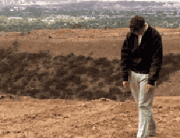 Person walking away from the camera on a barren landscape