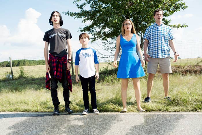 The Heffley family from the movie, dressed in casual attire, looking forward curiously on grass by a road