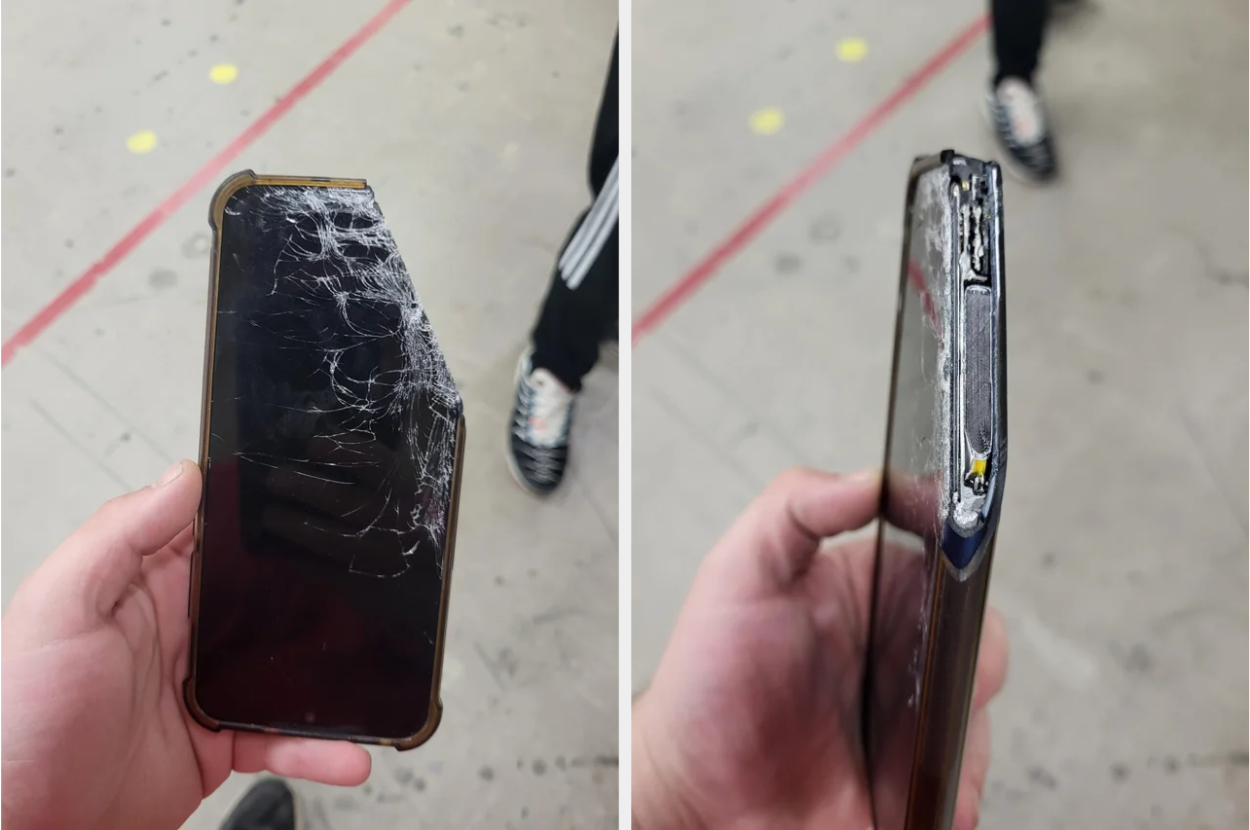 Person holding a broken smartphone with a cracked screen and damaged edges