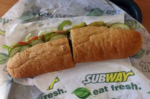 Subway sandwich on branded paper with assorted veggies and sliced bread