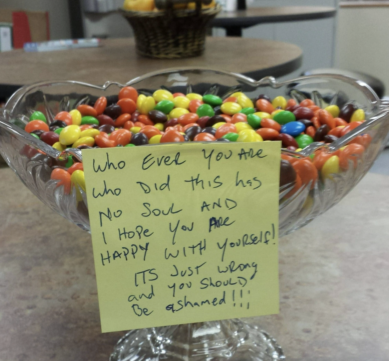 Bowl of candy-coated chocolate candies with an angry note about replacing original contents