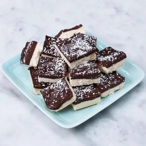 A plate of coconut-topped chocolate and vanilla layered bars