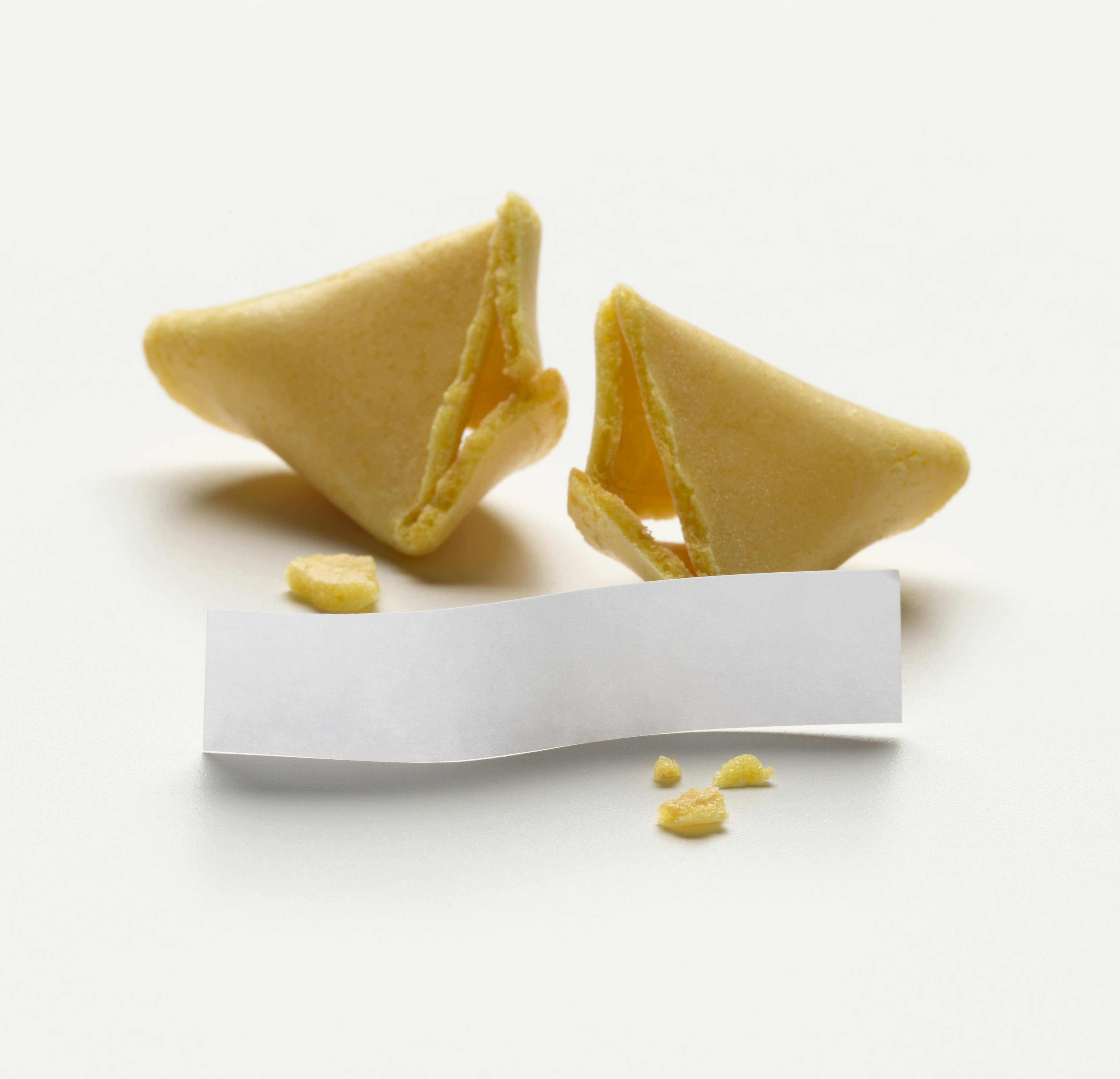 A broken fortune cookie with the visible paper fortune on a white background
