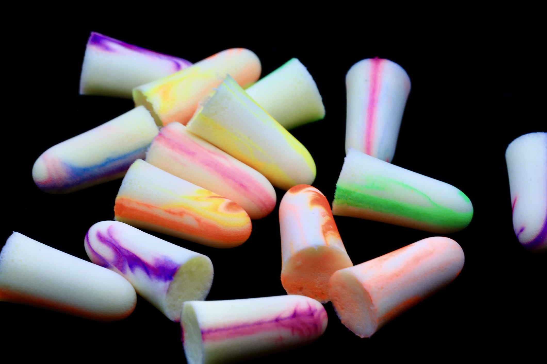 Assorted colorful earplugs scattered on a black background