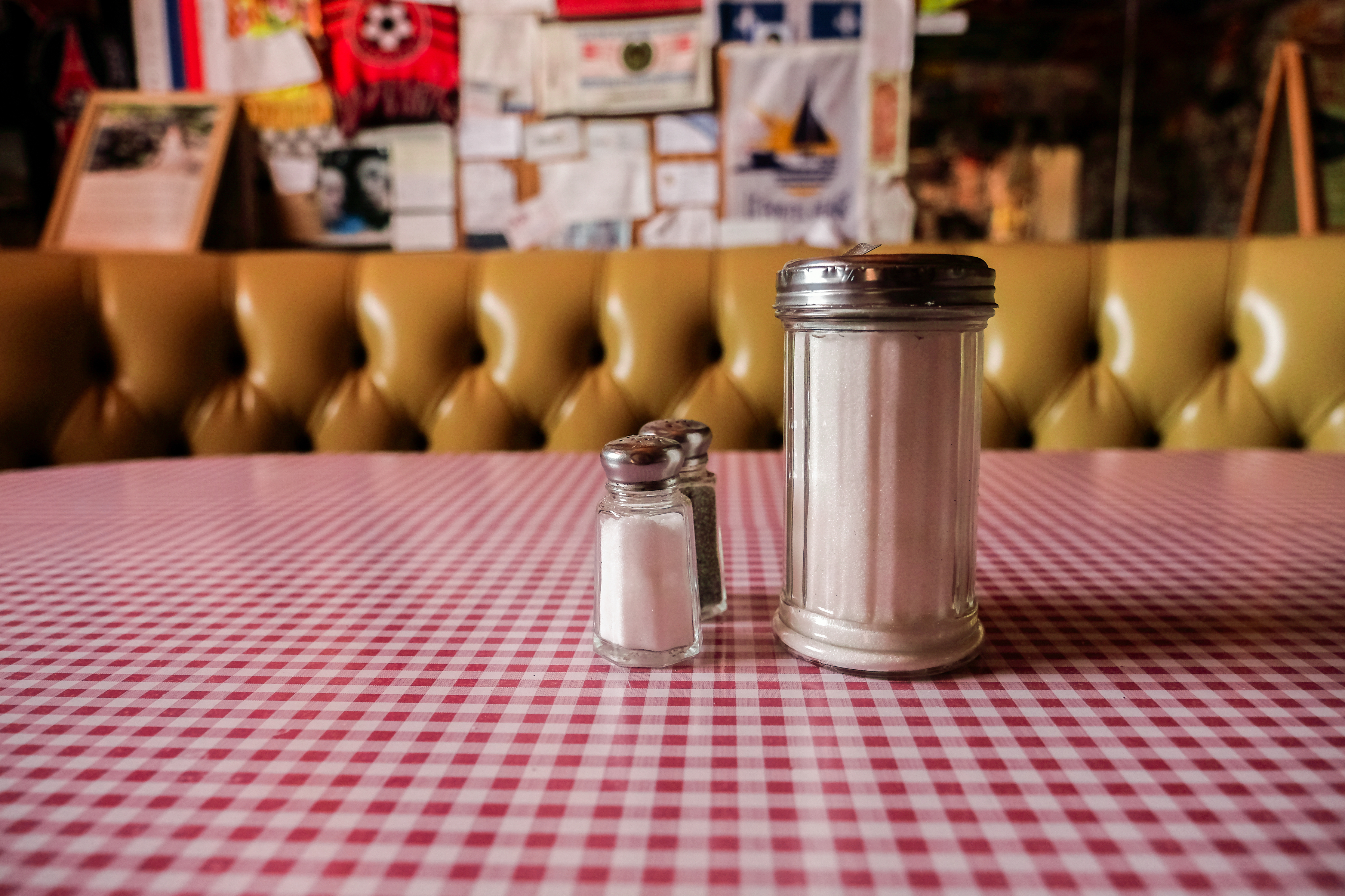 Salt shaker and sugar dispenser on a checkered tablecloth in a diner setting