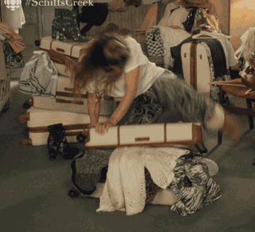 gif of alexis rose trying to close an overstuffed suitcase on the show schitt&#x27;s creek